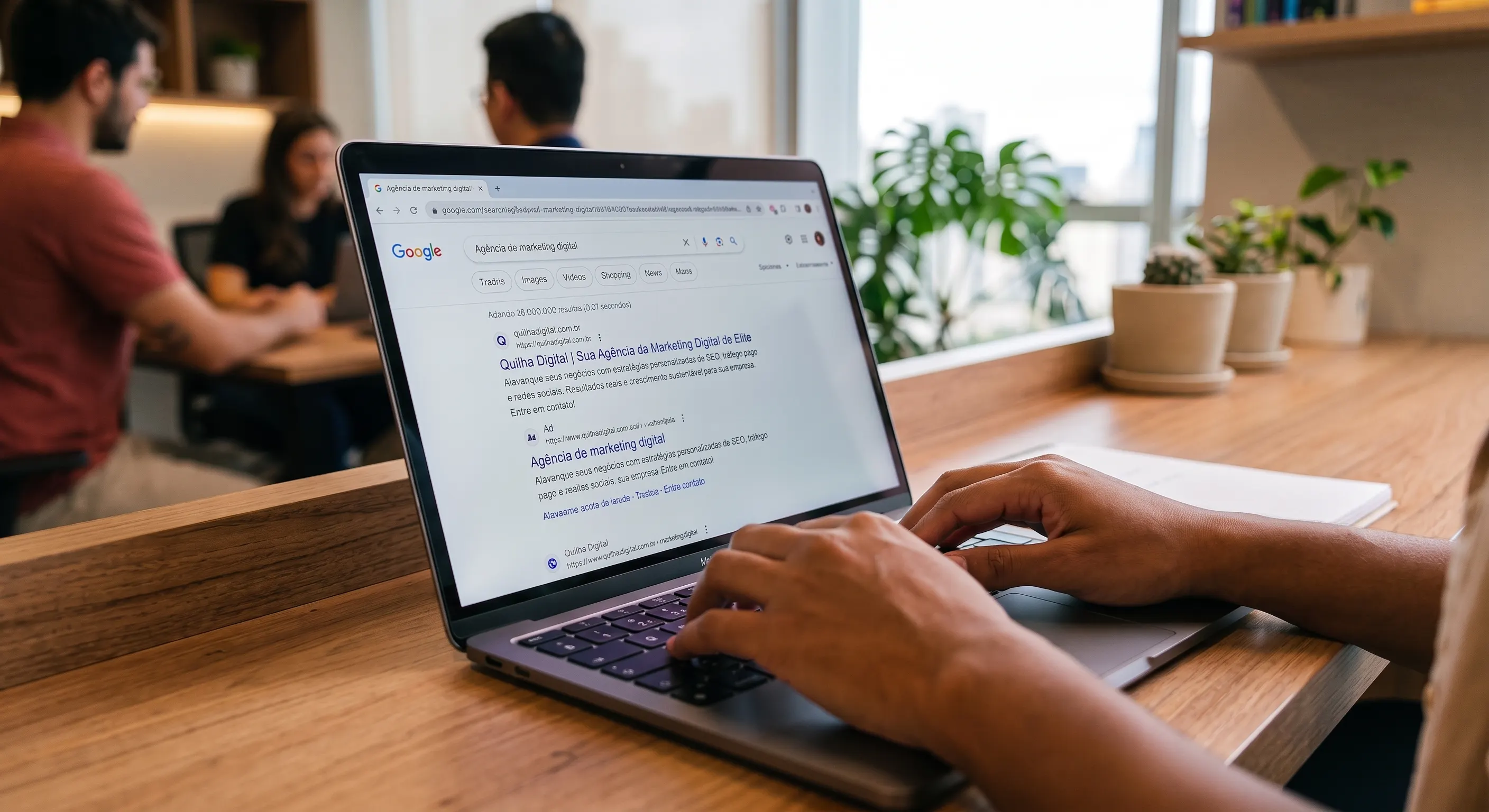 Notebook aberto numa mesa de escritório, com uma busca no Google por agência de marketing digital e o resultado da Quilha Digital na tela.